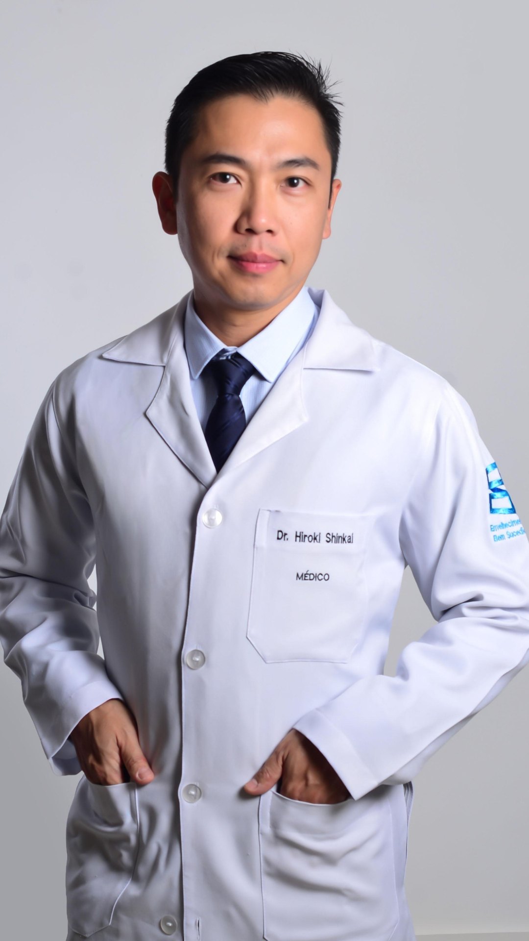 Dr. Hiroki Shinkai de jaleco branco com o bordado “Dr. Hiroki Shinkai · Médico”